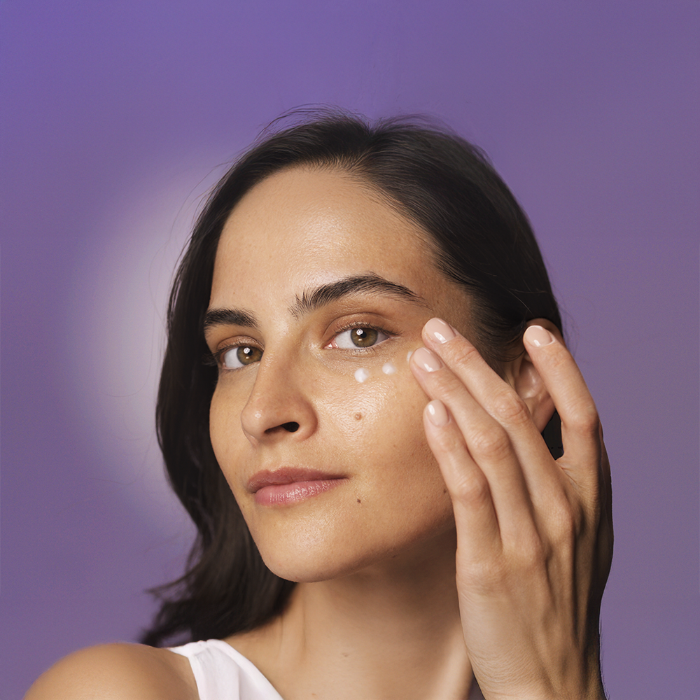 A woman applying HL/Skin Nourishing Eye Cream to her face.