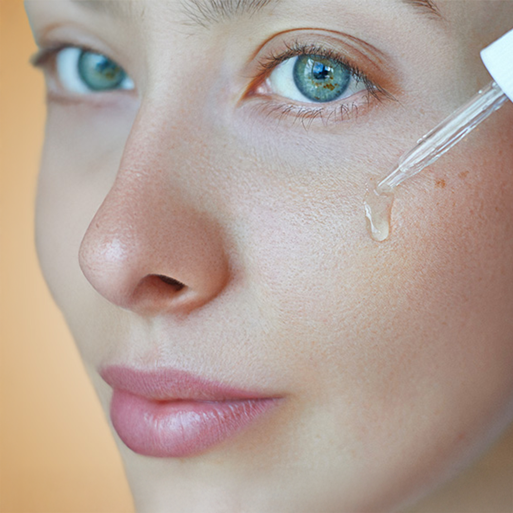 A woman applying HL/Skin Niacinamide Serum to her face.