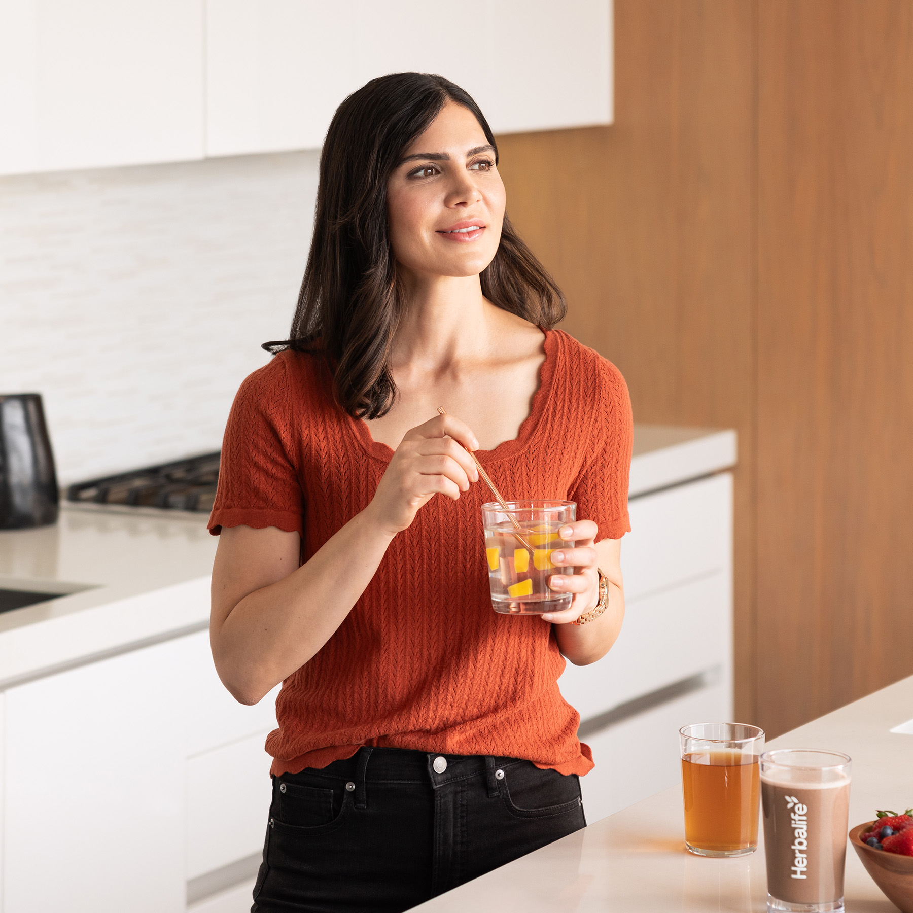 Woman stirring aloe drink in a glass in a modern kitchen while enjoying a healthy lifestyle