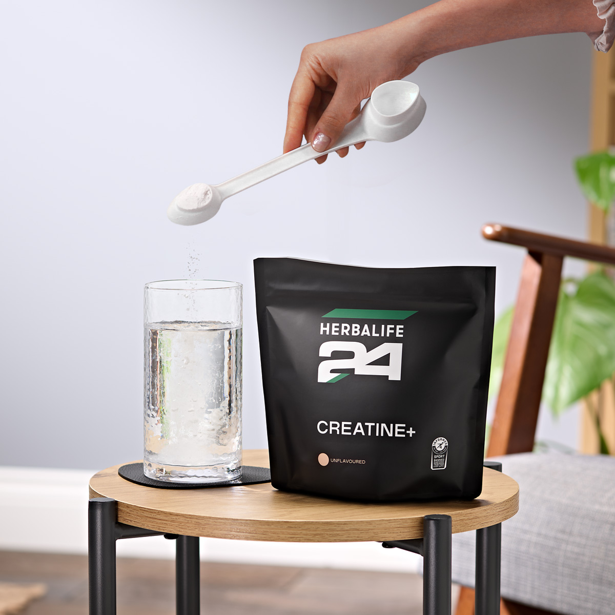 A woman making a glass of Herbalife24 Creatine+.