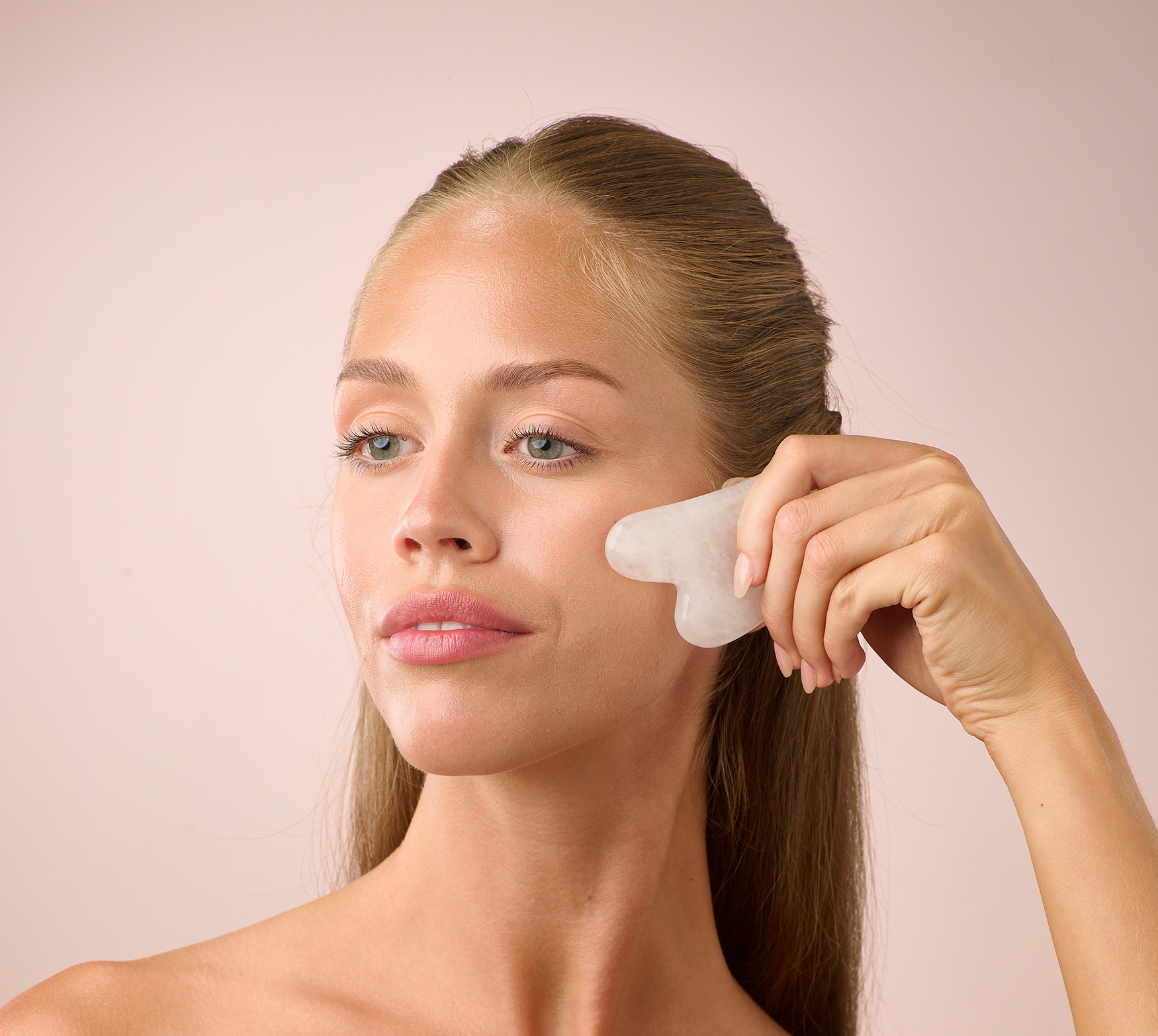 A woman using the HL/Skin White Jade Gua Sha Tool